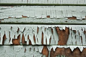 A close-up shot of a wood sided house with fading paint